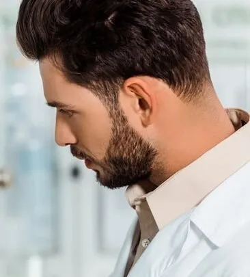Taper fade haircut blended into a full beard, side view