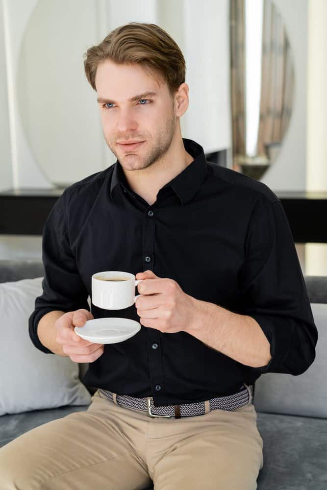 Positive casual man stepping to the side and looking to the camera while  wearing a white shirt and brown pants on white  CanStock