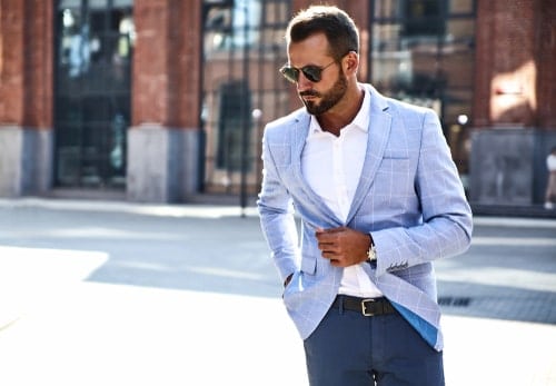 man walking down street wearing pink blazer over blue shirt with navy pants   AvenueSixty