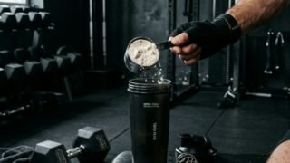 Man scooping protein powder into shaker at gym