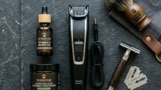 Men's stubble grooming products flat lay on dark stone